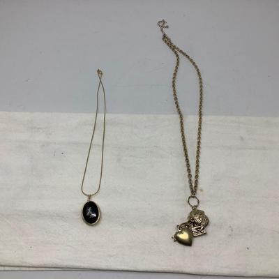 Sale Photo Thumbnail #253: Two gold necklaces one has black locket with gold inside.  The other is gold necklace with 5 charms.