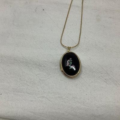 Sale Photo Thumbnail #254: Two gold necklaces one has black locket with gold inside.  The other is gold necklace with 5 charms.