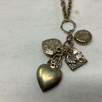 Sale Photo Thumbnail #257: Two gold necklaces one has black locket with gold inside.  The other is gold necklace with 5 charms.