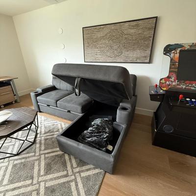 Sale Photo Thumbnail #22: The Kipling II Grey Sectional is a versatile addition to any living room, offering a seating capacity for three adults. This medium-firm sofa, upholstered in solid gray leather, features a high back and integrated cupholders for added convenience. The sec