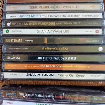 AN ASSORTMENT OF MAINLY COUNTRY WESTERN MUSIC ON CD AND A BASKET WITH A LID