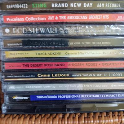 AN ASSORTMENT OF MAINLY COUNTRY WESTERN MUSIC ON CD AND A BASKET WITH A LID