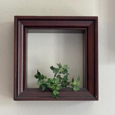 Three shadow box frames each containing artificial ivy.