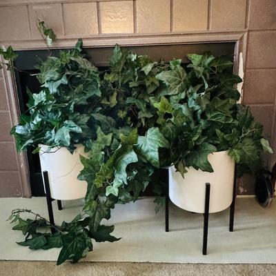 Two alto ceramic standing planters with artificial plants.