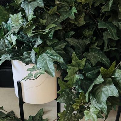 Two alto ceramic standing planters with artificial plants.