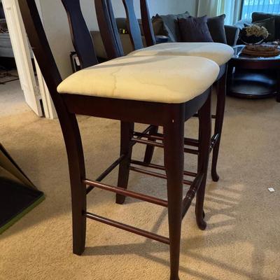 Two tall barstools, with seat covers.