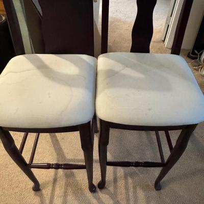 Two tall barstools, with seat covers.