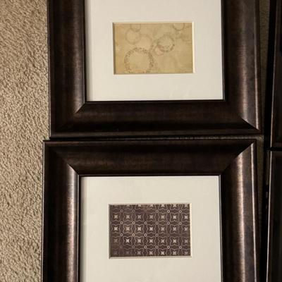Six framed art pieces, likely decorative prints or patterns, housed in dark wood frames with white matting.