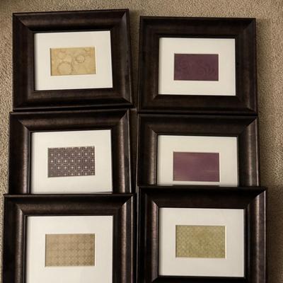 Six framed art pieces, likely decorative prints or patterns, housed in dark wood frames with white matting.