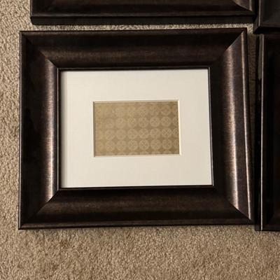 Six framed art pieces, likely decorative prints or patterns, housed in dark wood frames with white matting.