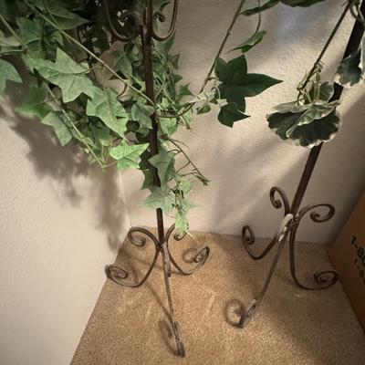 Decorative indoor plants, likely artificial ivy, housed in elegant metal stands.