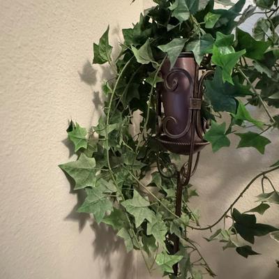 Decorative indoor plants, likely artificial ivy, housed in elegant metal stands.