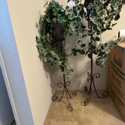 Decorative indoor plants, likely artificial ivy, housed in elegant metal stands.