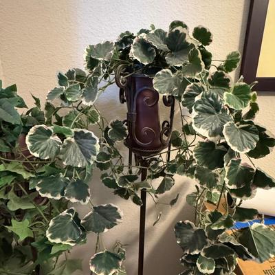Decorative indoor plants, likely artificial ivy, housed in elegant metal stands.
