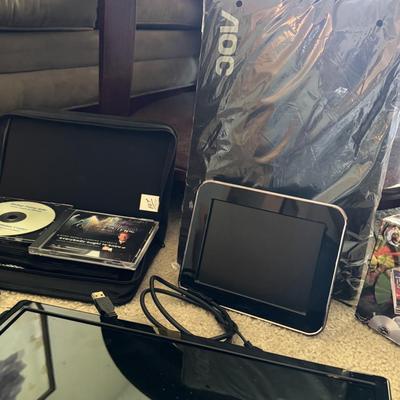 AOC portable monitor, The Dynamics of Faith" book by Peter Lowe, and a CD/DVD case with various discs.