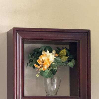 Three shadow boxes, a type of framed wall decor, each containing an arrangement of artificial flowers.