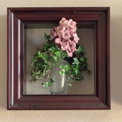 Three shadow boxes, a type of framed wall decor, each containing an arrangement of artificial flowers.