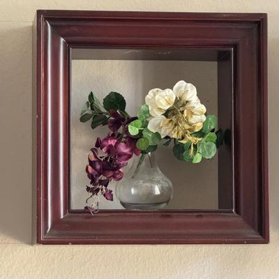 Three shadow boxes, a type of framed wall decor, each containing an arrangement of artificial flowers.