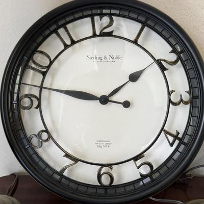 Pair of classic-style table lamps with cream-colored bell lamp shades and a large round wall clock with a dark frame and white face.
