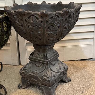 Two ornate, dark-colored decorative containers, commonly identified as planters or urns, likely made of cast iron.