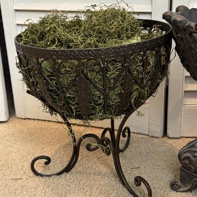 Two ornate, dark-colored decorative containers, commonly identified as planters or urns, likely made of cast iron.