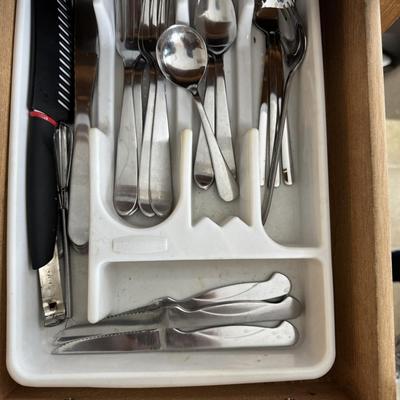 kitchen utensil drawer organizer containing various pieces of flatware and a large serving utensil.