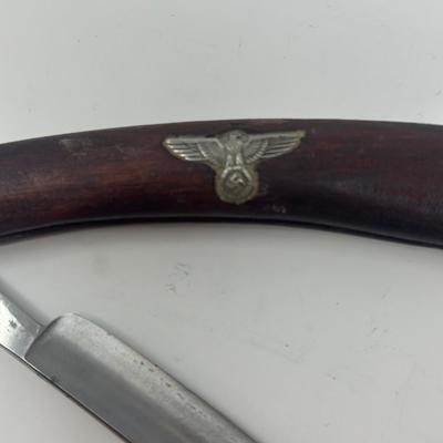 Sale Photo Thumbnail #416: In excellent condition, this vintage WWII NSDAP straight razor features a wood handle with a metal eagle and swastika emblem attached.