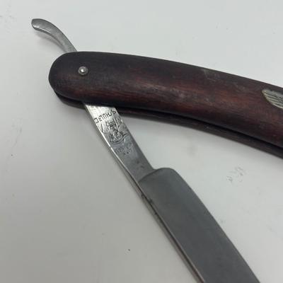 Sale Photo Thumbnail #415: In excellent condition, this vintage WWII NSDAP straight razor features a wood handle with a metal eagle and swastika emblem attached.