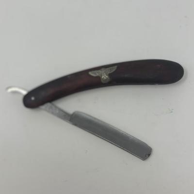 Sale Photo Thumbnail #414: In excellent condition, this vintage WWII NSDAP straight razor features a wood handle with a metal eagle and swastika emblem attached.