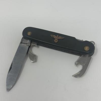 Sale Photo Thumbnail #424: Well used WWII German multi tool with an eagle and swastika emblem attached.