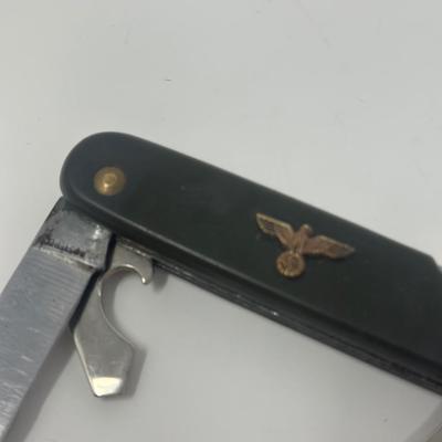Sale Photo Thumbnail #425: Well used WWII German multi tool with an eagle and swastika emblem attached.