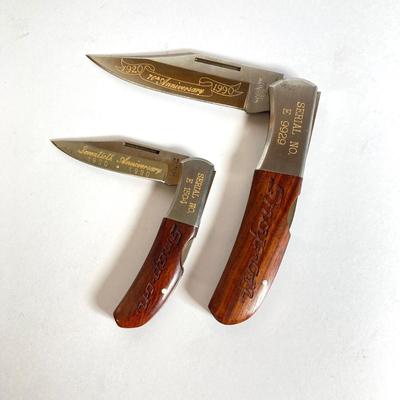 LOT 159: Kershaw 70th Anniversary Knives Serial No. E 1504 and E 9929, Sheaths and Pewter Pete Kershaw Numbered Belt Buckle