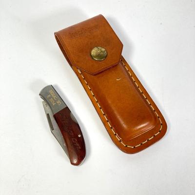 LOT 159: Kershaw 70th Anniversary Knives Serial No. E 1504 and E 9929, Sheaths and Pewter Pete Kershaw Numbered Belt Buckle