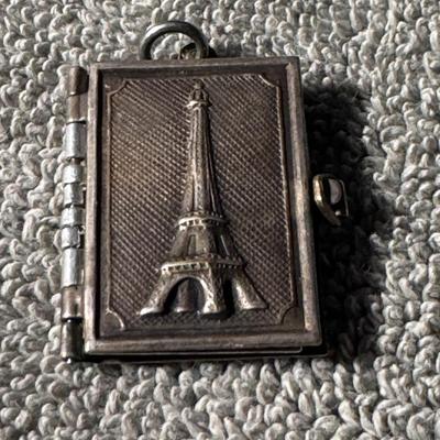 Sale Photo Thumbnail #41: vintage Paris souvenir book locket featuring the Eiffel Tower. This type of locket often opens to reveal miniature photos or engravings related to Paris or personal memories. 
Here's what you might want to know about it:
Type: It's a locket designed to re