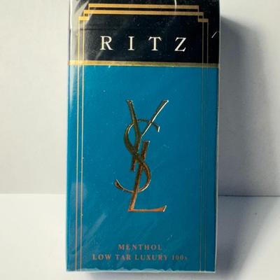 Sale Photo Thumbnail #675: Vintage pack of Ritz Menthol cigarettes, a brand that was introduced in the mid-1980s by R.J. Reynolds Tobacco Company in collaboration with the renowned fashion house Yves Saint Laurent (YSL). 
Here's more information about this product:
Designer Collabo