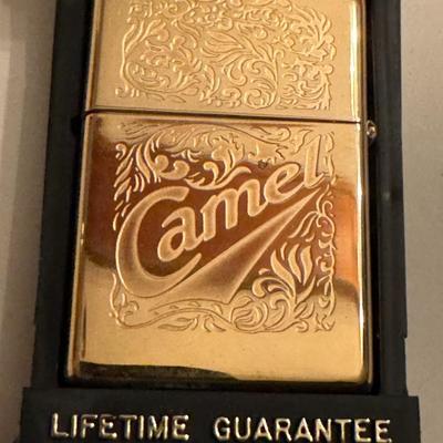 Sale Photo Thumbnail #45: Zippo Camel lighter. It's a vintage Zippo from 1995 featuring a detailed design, described as "22kt Luster Etch". This design process involves double etching into the brass lighter, with chrome applied to create a multi-dimensional effect. Some of the des