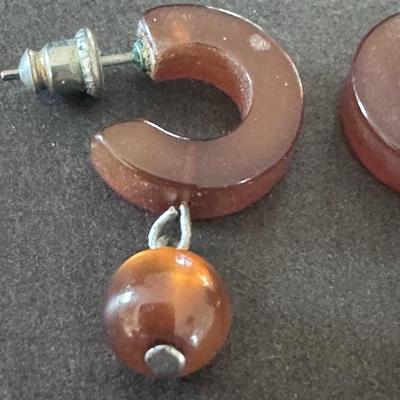 Sale Photo Thumbnail #351: Chloe Hoops in Amber, a style of earring featuring chunky, C-shaped  hoops in a warm, amber color, often with a marbled or semi-transparent finish. 
Key features and details:
Design: They boast a modern, chunky silhouette with an open hoop style, crafted 