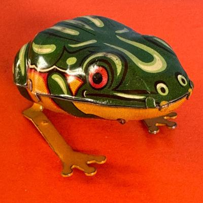 Sale Photo Thumbnail #289: A vintage German D R G M  tin frog wind-up toy, likely from the 1940s. 
Product Information:
Name: Vintage German Tin Frog Wind Up Toy
Origin: Made in Germany
Era: 1940s
Type: Wind-up/Clockwork mechanism tin toy
Description: This charming toy is made with