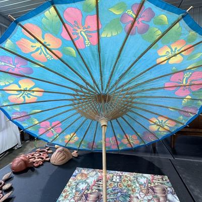 Sale Photo Thumbnail #694: blue paper parasol decorated with hibiscus flowers, likely of Asian origin, possibly Japanese or Chinese. These parasols are traditionally crafted from materials such as bamboo and rice paper. 
Key details about the parasol:
Design: It features hand-paint