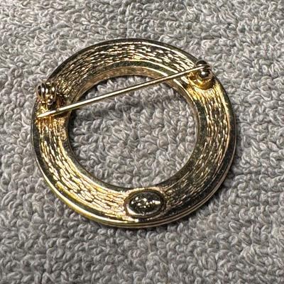 Sale Photo Thumbnail #413: vintage gold tone rhinestone circle brooch.
Here's a breakdown of its features and potential information:
Design: It's a classic circular brooch, likely from the mid-20th century (e.g., 1950s-1960s), adorned with sparkling rhinestones set in a gold-tone m