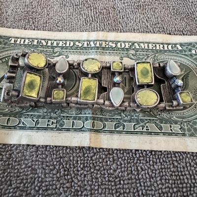 Sale Photo Thumbnail #476: Lia Sophia stretch bracelet featuring green and light blue glass or crystal stones set in a silver-tone, possibly matte or pewter-toned, metal. 
More specifically, it appears to be a style similar to the "Lia Sophia Pretty Green Foil Glass & Blue Stretch 