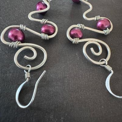 Sale Photo Thumbnail #556: Dark Pink Glass Pearl Twisted Drop Earrings, characterized by their handmade, wire-wrapped design. 
Key features of these earrings:
Materials: They primarily consist of dark pink or purple glass pearls and a silver-toned metal wire, likely silver-plated o
