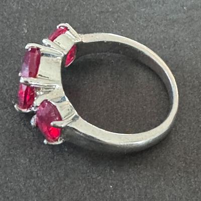 Sale Photo Thumbnail #585: three-stone ring featuring vibrant red gemstones, likely rubies or red rhinestones/cubic zirconia, set in what appears to be a silver-toned metal, possibly sterling silver. 
Here's more information about this type of ring:
Design & Materials: It's a three