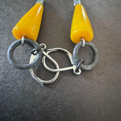 Sale Photo Thumbnail #592: dangle earrings featuring yellow, conical or teardrop-shaped elements, likely made of resin or a similar material, resembling polished amber.