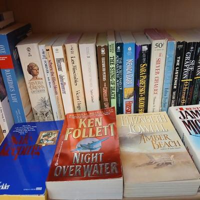 Two shelves of paperback books - Aaron Elkins - Elizabeth Lowell - James Herriot - Great for winter reading!