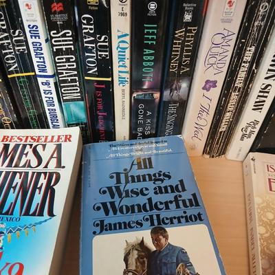 Two shelves of paperback books - Aaron Elkins - Elizabeth Lowell - James Herriot - Great for winter reading!