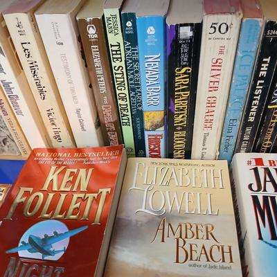 Two shelves of paperback books - Aaron Elkins - Elizabeth Lowell - James Herriot - Great for winter reading!