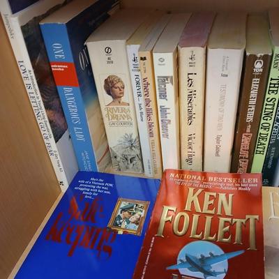 Two shelves of paperback books - Aaron Elkins - Elizabeth Lowell - James Herriot - Great for winter reading!