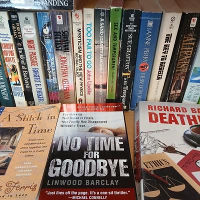 Two shelves of paperback books - Aaron Elkins - Elizabeth Lowell - James Herriot - Great for winter reading!