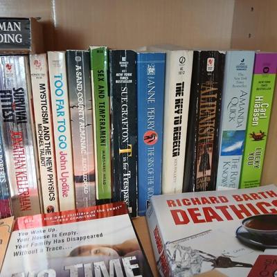 Two shelves of paperback books - Aaron Elkins - Elizabeth Lowell - James Herriot - Great for winter reading!